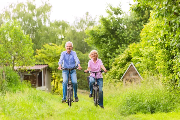 Seniors exercising with bicycle — Stock Photo, Image