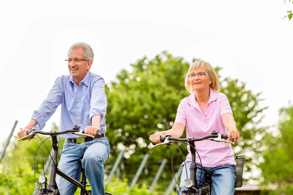 Seniors exercising with bicycle — Stock Photo, Image