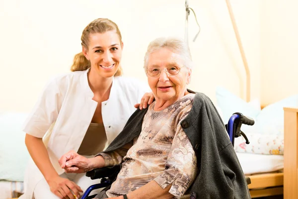 Enfermera y mujer mayor en un asilo de ancianos — Foto de Stock