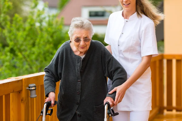 Verpleegkundige en vrouwelijke senior met walking frame — Stockfoto