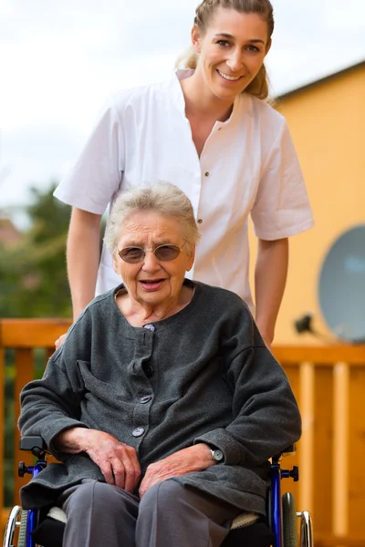 Jonge verpleegster en vrouwelijke senior in een rolstoel — Stockfoto