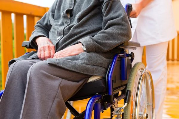 Ung sjuksköterska och kvinnliga senior i en rullstol — Stockfoto