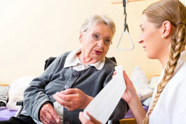 Nurse taking care of senior woman in retirement home — Stock Photo, Image