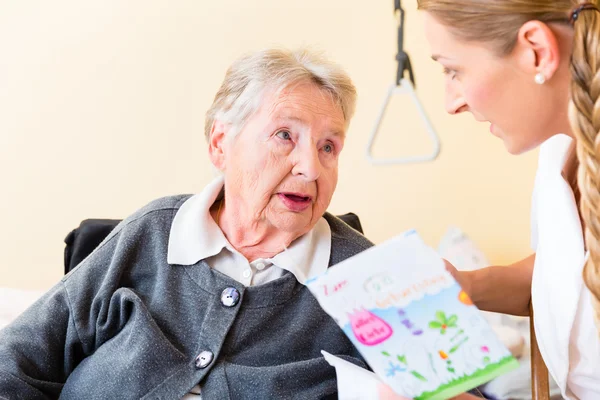 Nurse giving birthday card to senior woman in home — Stock Photo, Image