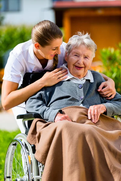 Mulher idosa em casa de repouso com enfermeira no jardim — Fotografia de Stock