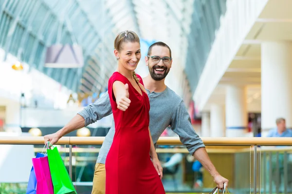 Hombre y mujer en centro comercial con bolsas —  Fotos de Stock