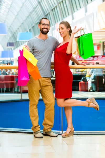 Hombre y mujer en centro comercial con bolsas —  Fotos de Stock