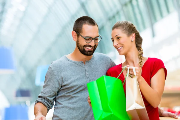 Homem e mulher em shopping center com sacos — Fotografia de Stock