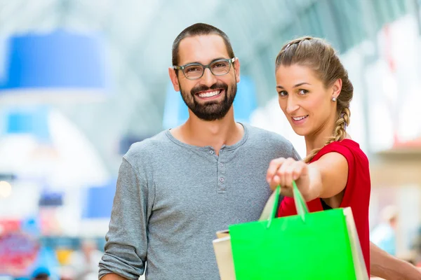 Homem e mulher em shopping center com sacos — Fotografia de Stock
