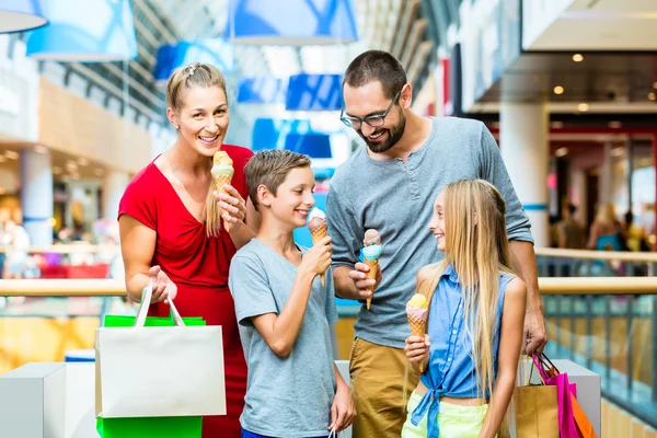 Familjen äta glass i köpcentrum med väskor — Stockfoto