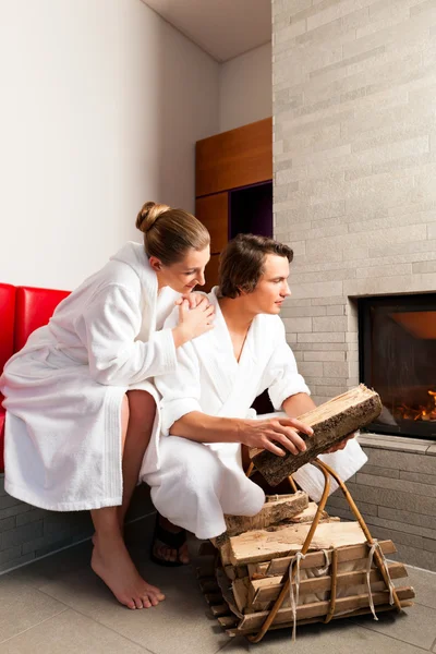 Junges Paar sitzt im Bademantel am offenen Kamin — Stockfoto