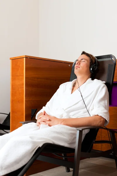 Hombre joven relajándose en el spa con música — Foto de Stock