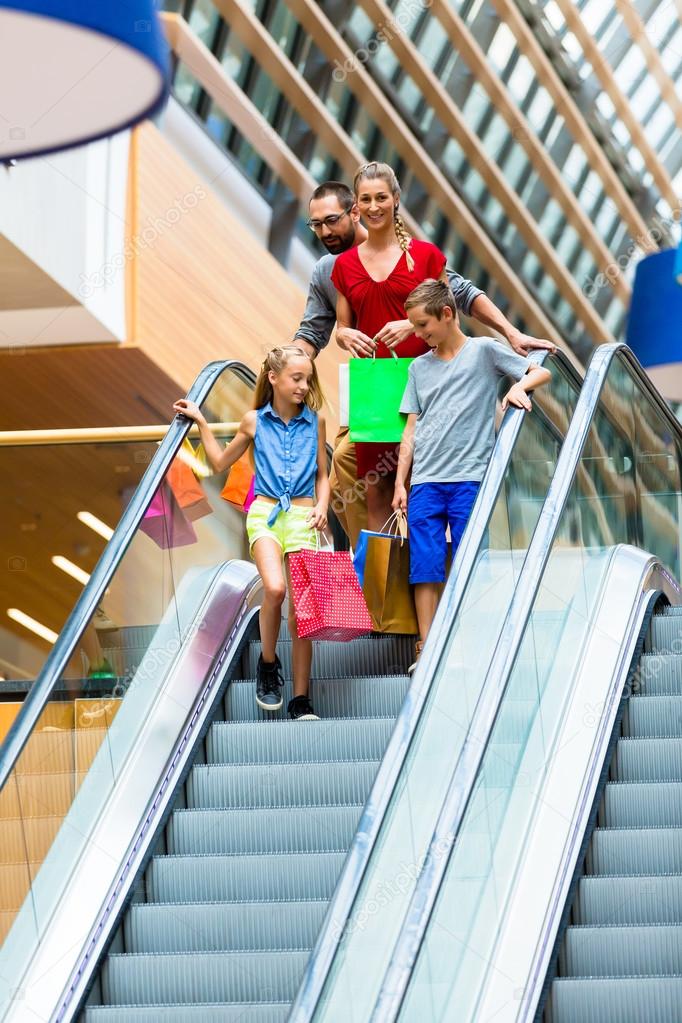 Family in shopping mall on escalators with bags