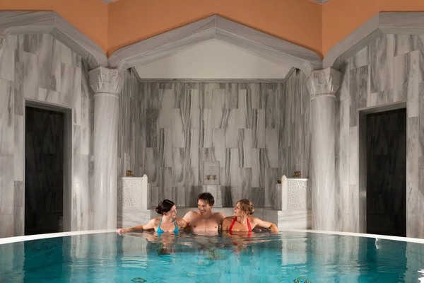 Three friends in swimming pool or thermal bath