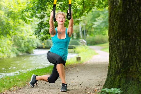 Mujer haciendo suspensión honda entrenador deporte — Foto de Stock