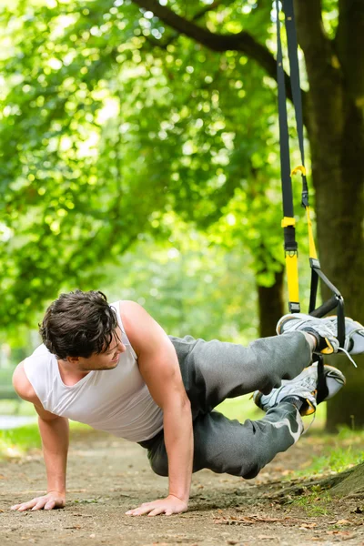 Man in city park doing suspension trainer sport — Stock Photo, Image