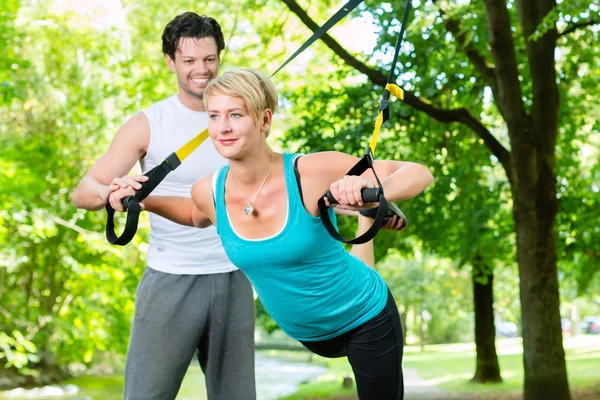 People in park on suspension or sling trainer