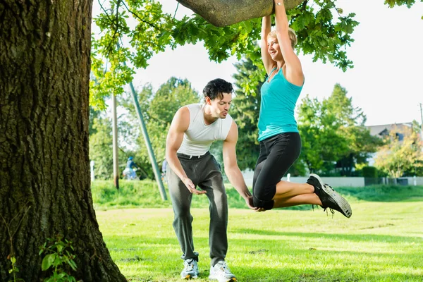 Mensen in stadspark doen kin of pull ups op boom — Stockfoto