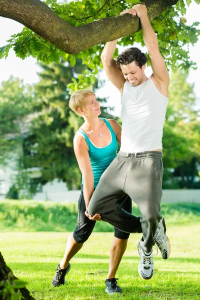 Mensen in stadspark doen kin of pull ups op boom — Stockfoto