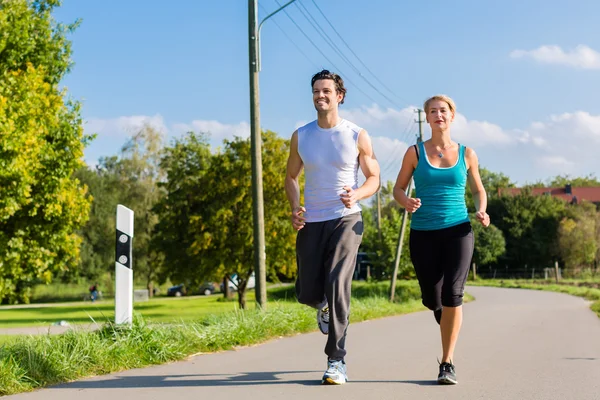 Deporte pareja corriendo y trotando en la calle rural — Foto de Stock