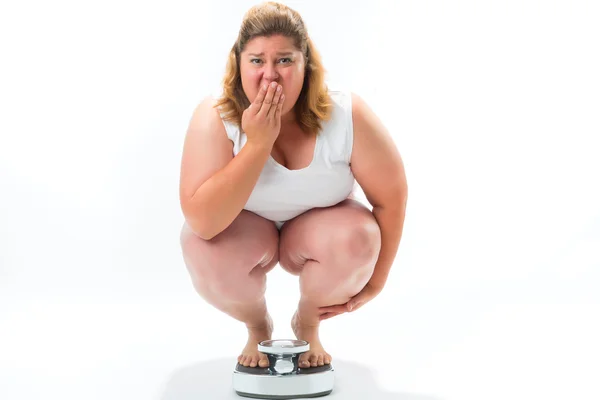 Obese young woman crouching on a scale — Stock Photo, Image