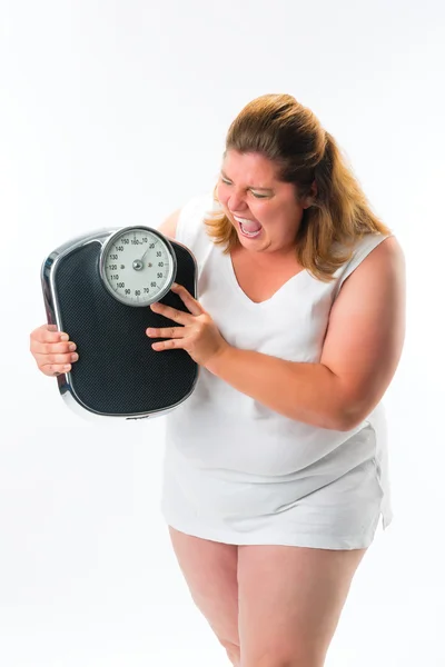 Ожирение женщина выглядит злой на масштабе — стоковое фото