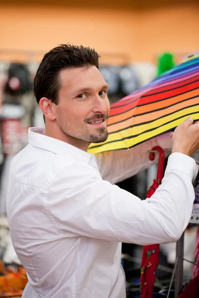 Przystojny mężczyzna kupując parasol w supermarkecie — Zdjęcie stockowe