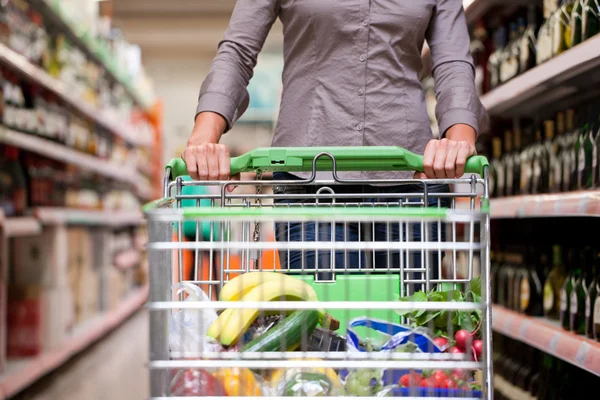 Fiatal nő, pushcart a szupermarketben — Stock Fotó