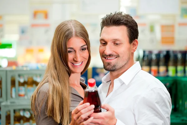 Couple in supermarket buying beverages — Stock Photo, Image