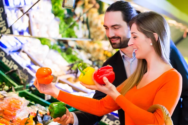 Couple sélectionnant des légumes en hypermarché — Photo