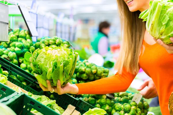 Vrouw koopt groenten in supermarkt — Stockfoto