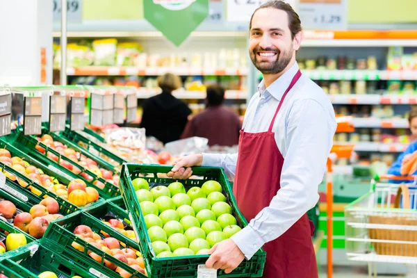 Hipermarket urzędnik wypełniając stojaki magazynowe — Zdjęcie stockowe