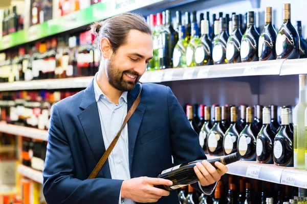 Man väljer vin i spritbutik — Stockfoto