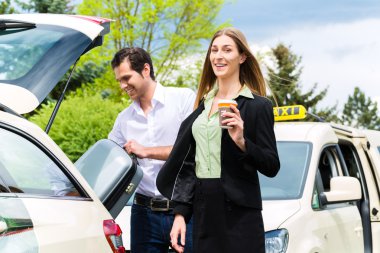 Young businesswoman in front of taxi clipart