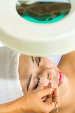 Asian woman getting a facial treatment in spa clipart