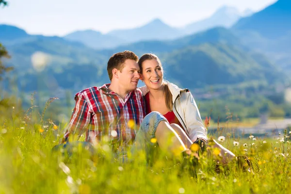 Paar zit in de weide met berg — Stockfoto