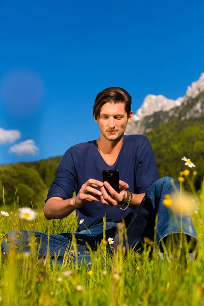 Hombre con teléfono sentado en las montañas —  Fotos de Stock