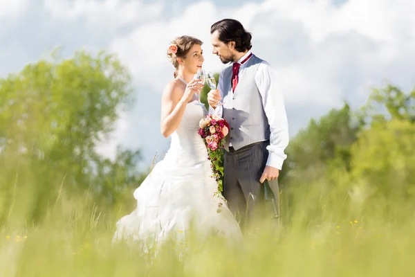 婚礼新娘和新郎在一块草地上，与新娘花束 — 图库照片