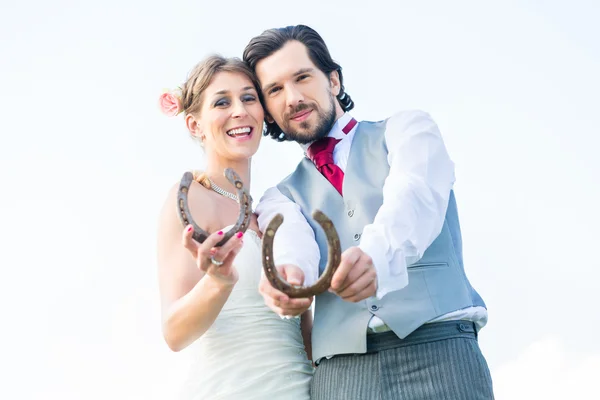 Свадебная пара показывает лошадиную обувь на удачу — стоковое фото