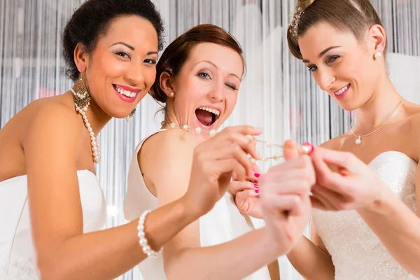 Las mujeres se divierten mientras que el vestido de novia encaja en la tienda —  Fotos de Stock