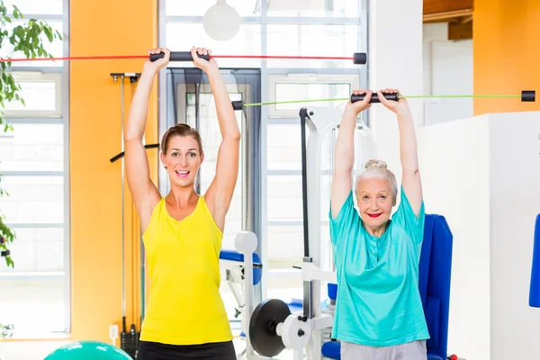 Young and old woman in gym training strength with rod — Stock Photo, Image