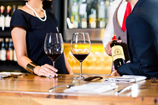 Asiático casal degustação de vinho tinto no bar — Fotografia de Stock