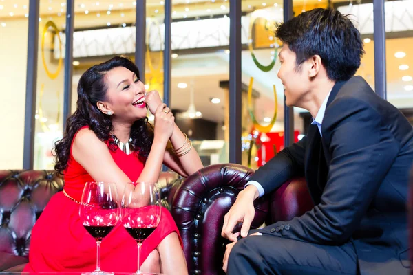 Asian couple sitting in bar chatting — Stock Photo, Image