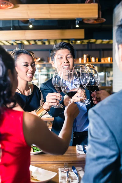 Aziatische vrienden roosteren met rode wijn in bar — Stockfoto