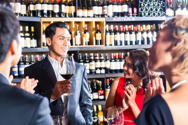 Amigos asiáticos brindando con vino tinto en el bar — Foto de Stock