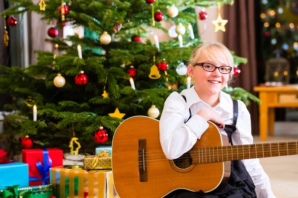 Dívka si hraje kytara na Štědrý den — Stock fotografie