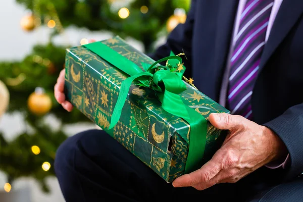 Senior man celebrating Christmas with present — Stock Photo, Image