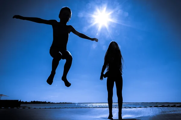 Two kids jumping on trampoline