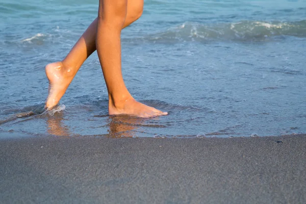 Ung kvinna ben på stranden vid solnedgången — Stockfoto