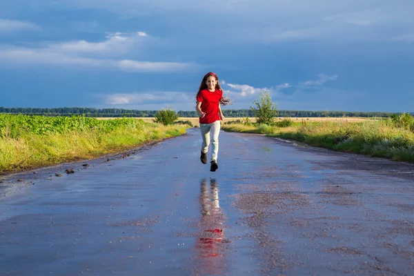 Ragazza felice che corre su strada bagnata — Foto Stock